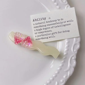 Dettaglio del fermaglio per capelli ondulato con due fragole rosa glitterate in resina