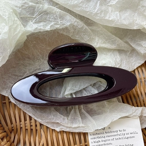 Detailed close-up of a large hollow oval claw clip in elegant glossy deep red resin