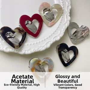 Detail shot of heart-shaped acetate hair clips in multiple colors on a ceramic tray