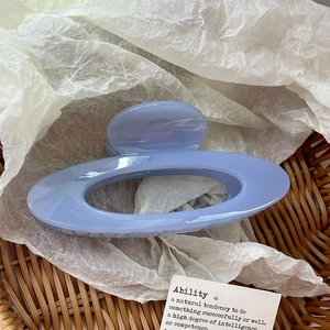 Detail view of a lavender oval hollow claw clip placed on a natural woven basket