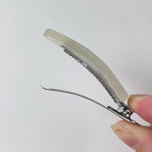 Detailed view of the silver metal alligator clip and light green acetate hair clip