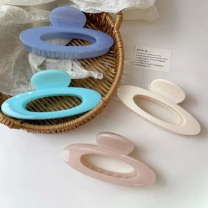 Elegant hollow oval hair claw clips in purple, blue, white, and pink set in a woven basket