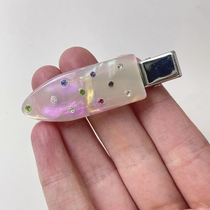 Detail of pink pearlescent acetate hair clip with sparkling colorful rhinestones