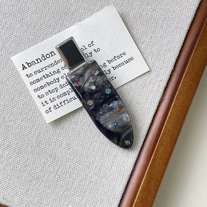 Close-up of marble acetate hair clip with colorful rhinestones on a card