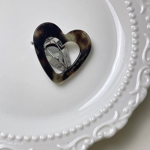 Detail of tortoiseshell heart hair clip showing acetate texture and metal duckbill clasp