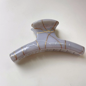 Detail of a purple translucent shark hair claw with gold vein pattern and lace texture