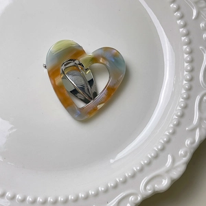 Close-up of heart-shaped marble acetate hair clip with gold Barrette la France text