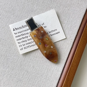 Detail view of acetate hair clip with amber texture and colorful rhinestones
