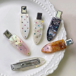 Elegant acetate hair clips set with rhinestones on a decorative white ceramic plate
