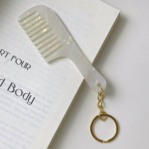 Elegant ivory marble acetate comb keychain with gold metal ring on open book