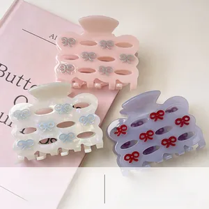 Close-up of acetate bow hair clips in pink and purple colors on a pink book