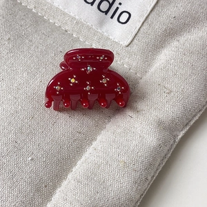 Gros plan d'une mini pince à cheveux bordeaux ornée de fleurs en strass brillants