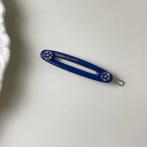 Nahaufnahme einer dunkelblauen Haarspange in Gelee-Farbe mit Strass und Goldaufschrift