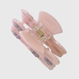 Close-up of pink acetic acid hair claw clip with purple bow and gold metal spring