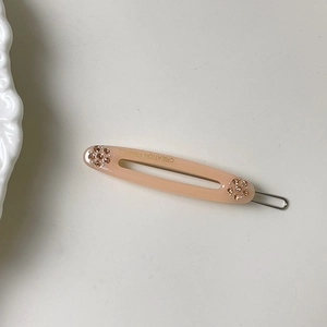 Makroaufnahme der rosa Haarspange mit funkelnden Strasssteinen und goldener Textgravur