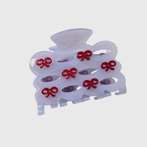 Detail view of a lavender acetate hair claw with delicate red 3D bow accents