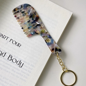 Detailed macro view of a marbled acrylic mini comb keychain with golden metal ring