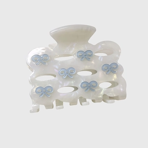 Detail of acetic acid hair claw clip with pearlescent finish and blue bow designs