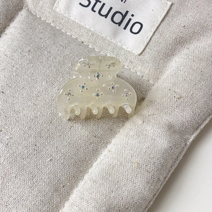 Détail macro d'une pince à cheveux en acétate crème avec des strass étincelants