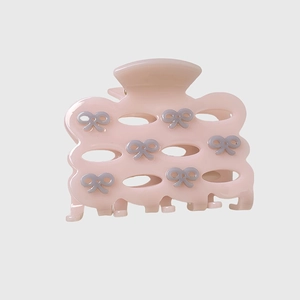 Detailed macro view of pink acetate hair claw clip with grey bow design and hollow texture