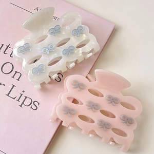 Close-up of elegant acetate hair claws with 3D bows and hollow-out wave design
