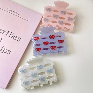 Detailed view of acetic acid hair claw clips in three pastel colors with bow designs