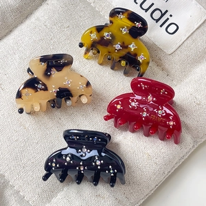 Mini pinces à cheveux demi-lunes avec strass en quatre couleurs sur un sac