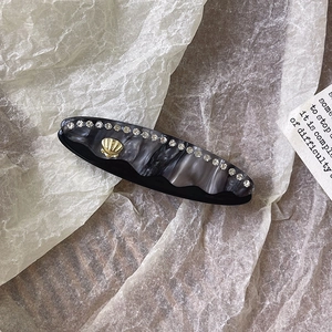 Dettaglio molletta per capelli effetto marmo con strass ed elemento a conchiglia dorata