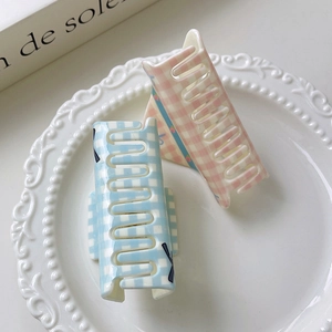 Detailed view of floral plaid bow hair claws in soft pastel blue and pink acrylic finish