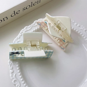 Detail of pink and blue checkered hair claws with bow patterns in a white ceramic dish