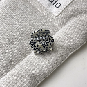 Macro shot of acetate hair claw clip with black-white spots and tiny pearl accents