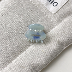 Detailed macro view of a mini blue marble hair claw clip with four white pearls