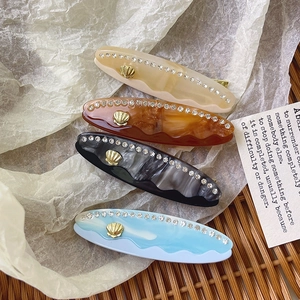Elegante fermaglio in acetato marmorizzato con strass e dettaglio conchiglia dorata