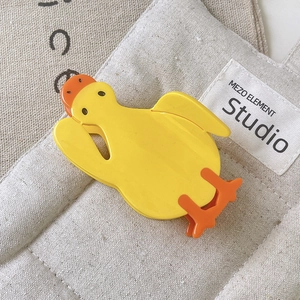 Macro view of a cute yellow duck-shaped hair claw clip made of polished acetate