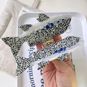 Dettaglio dei fermagli per capelli a forma di pesce con motivo leopardato in acetato