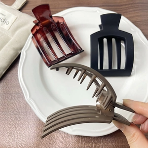 Three matte rectangular hair clips in black, brown, and grey displayed on a white plate