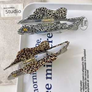 Dettaglio macro di pinze per capelli in acetato a forma di pesce con motivi maculati