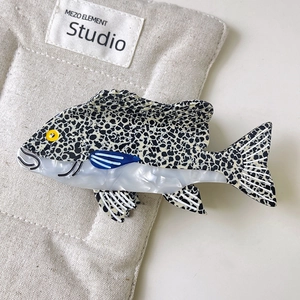Dettaglio molletta per capelli a forma di pesce con macchie leopardate e finitura perlata