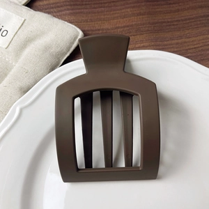 Detail view of square hollow hair clip with dark brown matte finish on a ceramic plate