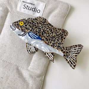 Dettaglio macro di un fermaglio per capelli in acetato a forma di pesce con macchie leopardate
