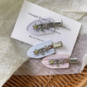 Detalle de tres pinzas para el cabello de acetato con flores metálicas y pequeños cristales