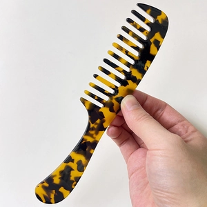 Detail of tortoiseshell acetate hair comb with wide teeth and ergonomic handle