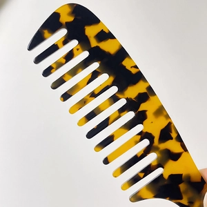 Close-up of wide-tooth acetate hair comb featuring premium amber tortoiseshell texture