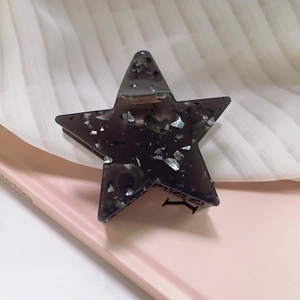 Close-up of a translucent dark grey star hair claw clip with embedded silver sequins