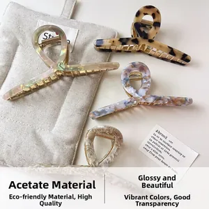 Detail of four acetate hair claws in tortoise shell and marble patterns on white surface