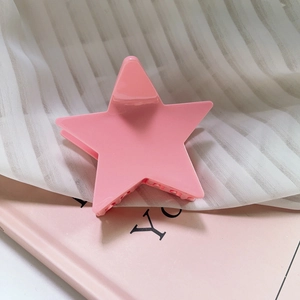 Macro shot of a glossy pink star-shaped hair claw clip on soft fabric background