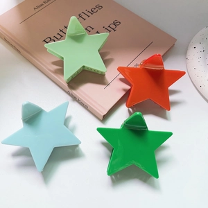 Close-up of four colorful star-shaped hair claws in glossy mint, orange, and blue finishes