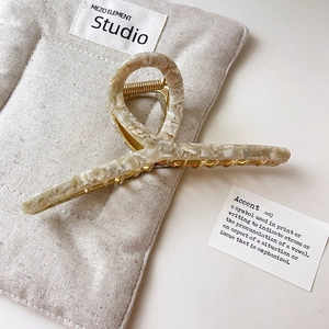 Close-up of cream marble acetate hair claw clip on linen pouch with golden metal spring