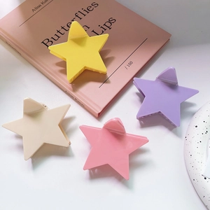 Macro detail of colorful star-shaped hair claws in macaron tones on a decorative surface