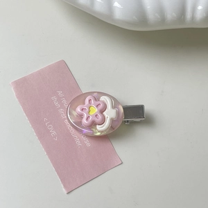 Detail of pink resin flower hair clip with glitter base and silver metal duckbill grip